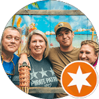 Four people smiling in front of a tropical backdrop with a tiki torch and star.